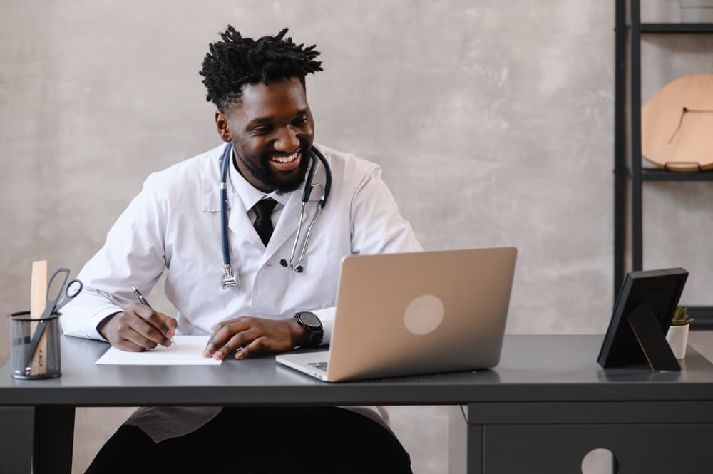 African American male doctor smiling at laptop