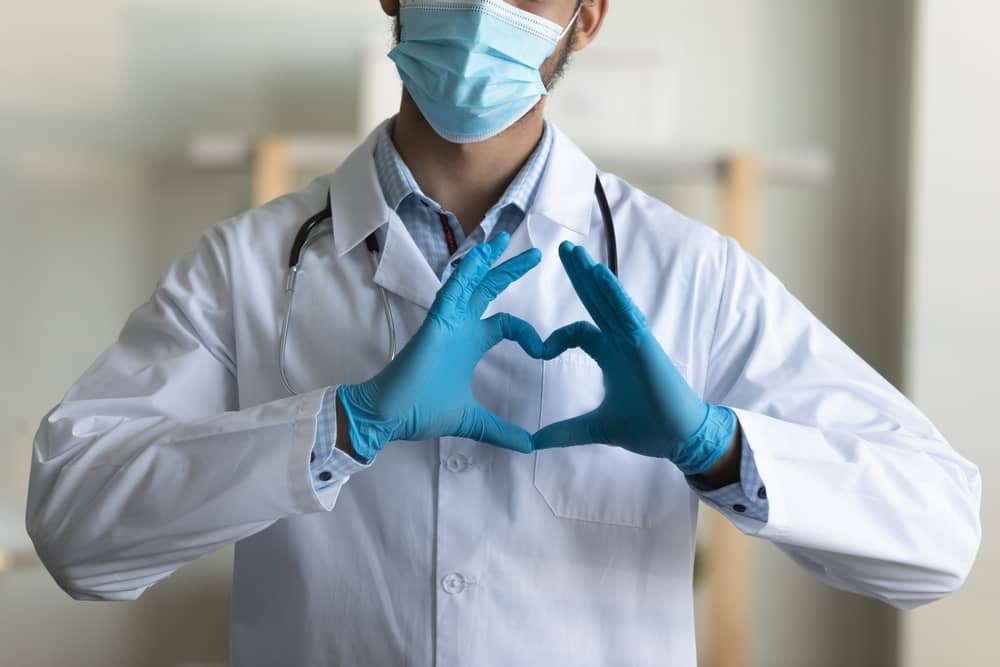 Male doctor making heart symbol with hands on chest