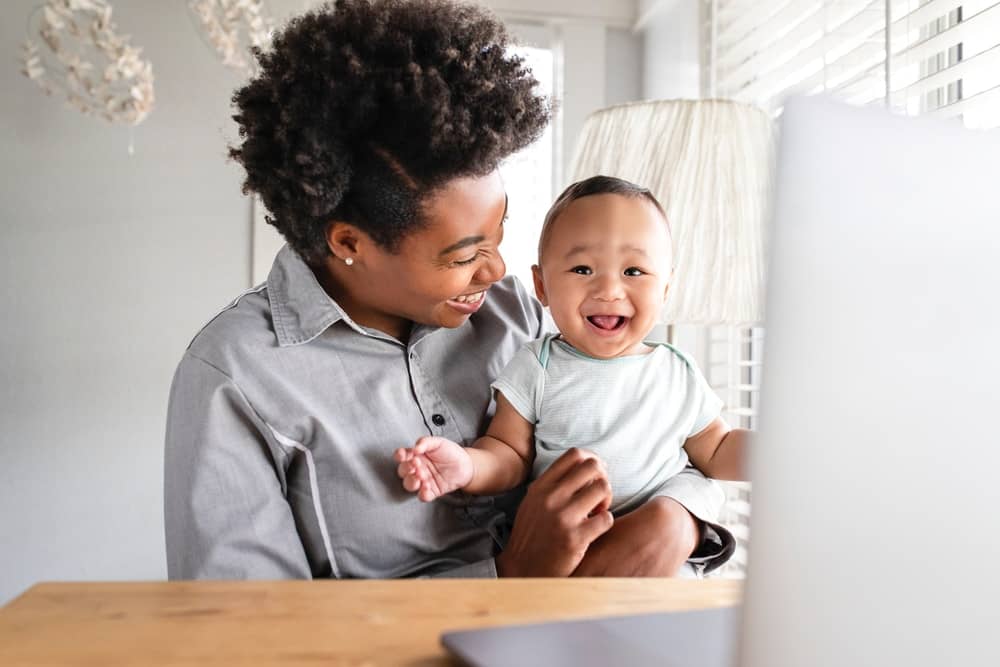 Woman with baby sitting in front of a laptop
