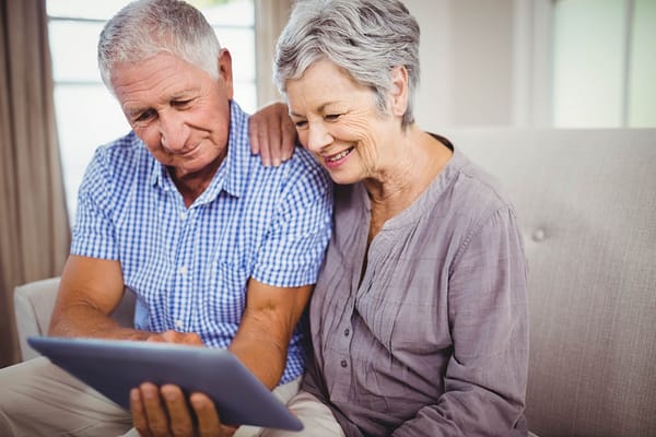 Old couple smiling looking at iPad